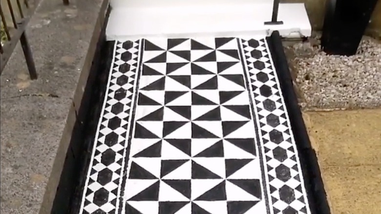 A black and white geometric print painted on an outdoor pathway.