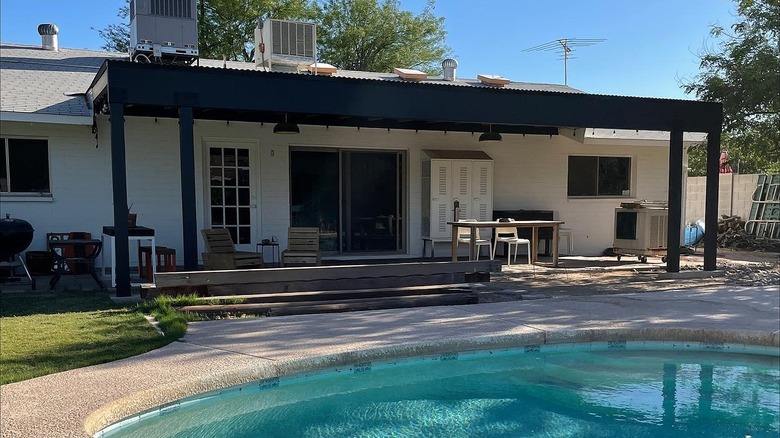 A house freshly painted white to contrast with the black awning over the poolside deck.