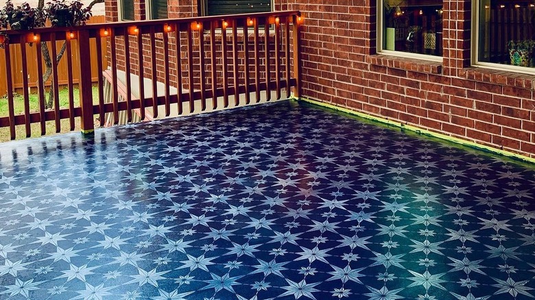 A blue stenciled pattern on an outdoor patio concrete slab.