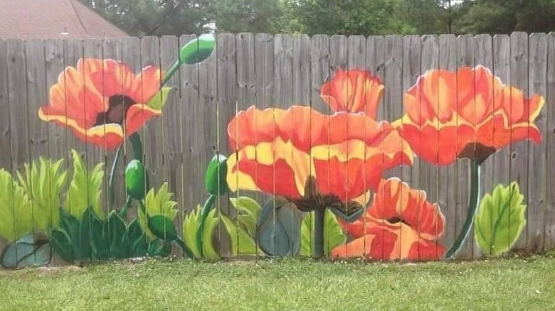 A floral mural painted on a wood fence in someone's backyard.