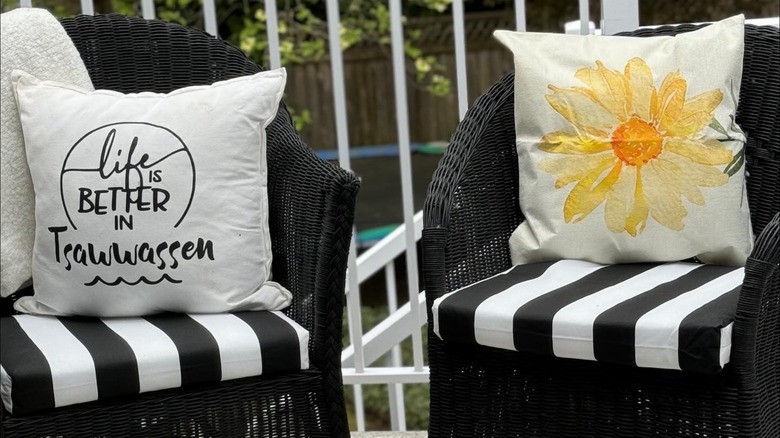 Wicker patio furniture painted black and adorned with decorative cushions.