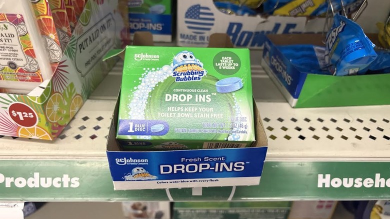 Scrubbing bubbles toilet drop-in cleaner hanging off metal store shelf