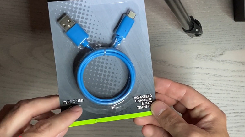 Man holding dollar store type USB-C charger still in packaging