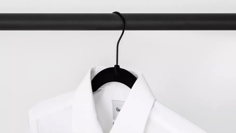 A black flocked hanger used to hang a dress shirt