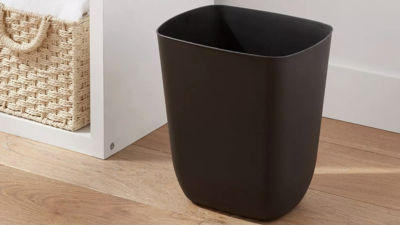 A black plastic trash can without a lid