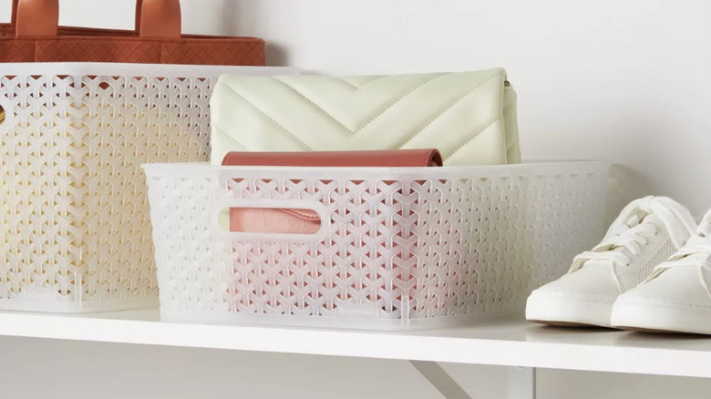 A translucent storage basket being used to hold small purses in a closet