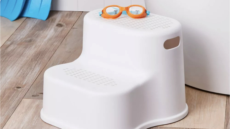 A white plastic step stool with goggles sitting on top