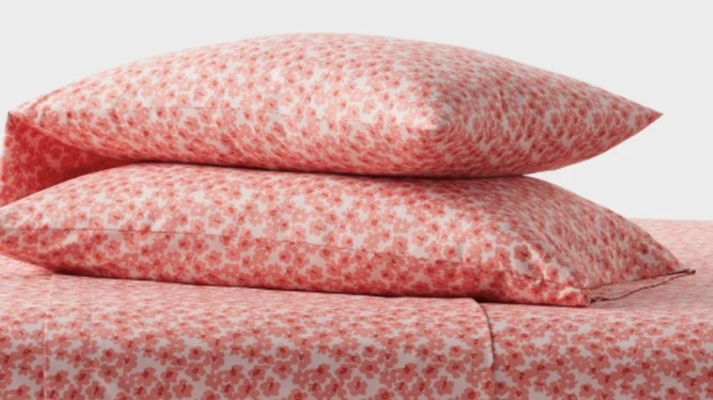 Two pillows sitting on top of a bed made with pink patterned sheets