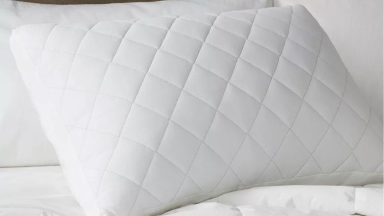 A pillow insert with a diamond pattern sitting on a bed