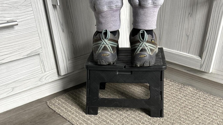 A person standing on a folding step stool.