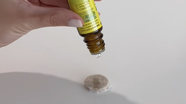 A person adds drops of essential oil to an adhesive felt pad.