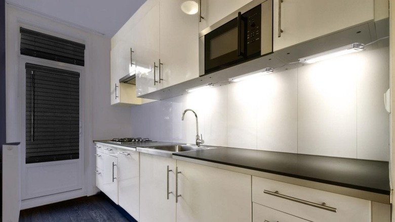 A small kitchen with strip lights underneath the cabinets.