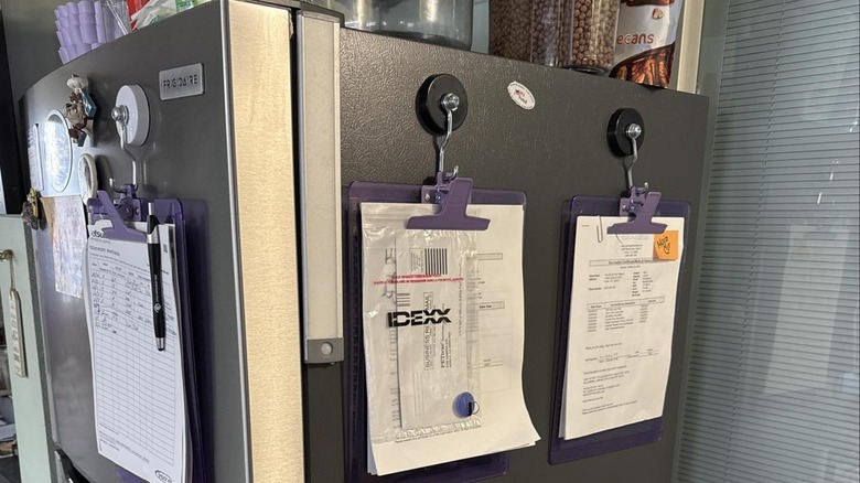 Magnetic hooks attaching clipboards to a fridge.