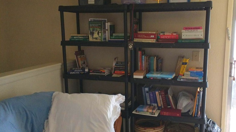 A storage rack fill of books in a bedroom.