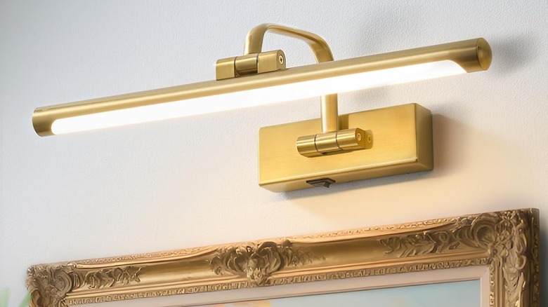 A battery-powered wall light illuminating artwork on a wall