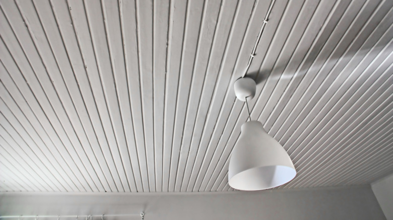 A white beadboard ceiling with a white light fixture