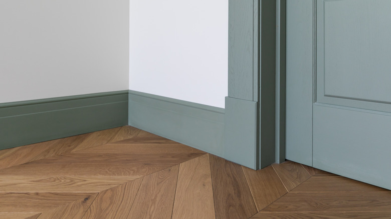 A door, frame, baseboards, and door plinth all in a matching shade of green