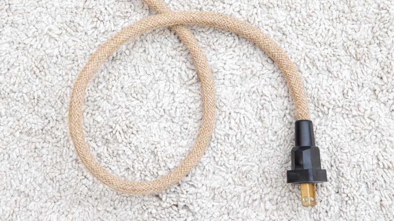 A woven fabric power cord on carpet