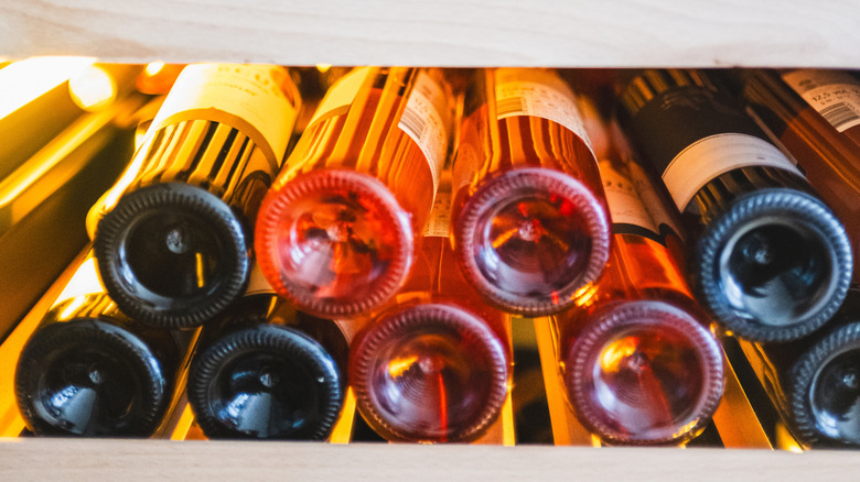 Wine bottles on their sides chill on a shelf.