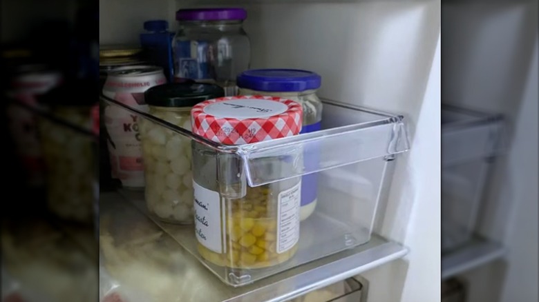 Cans and jars of food are organized in a plastic bin.