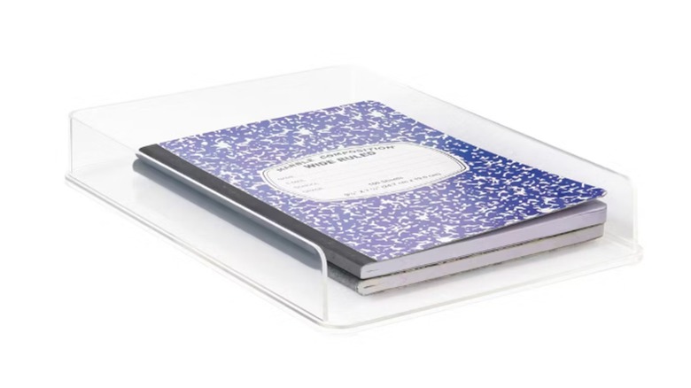 A couple of notebooks are stacked in a clear letter tray.