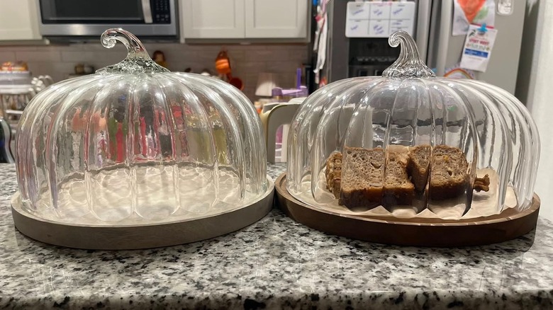 Aldi and Pottery Barn pumpkin-shaped cake dome's next to each other on counter
