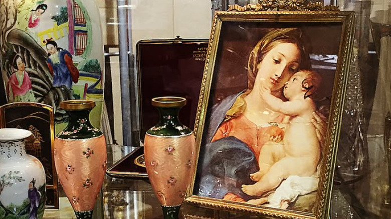 A vintage painting of a woman and a child on a table with other antiques.