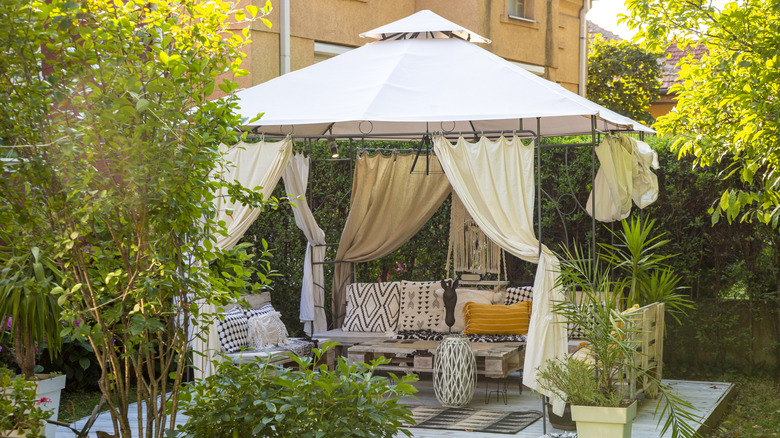 A gazebo in a garden with plenty of plants providing privacy