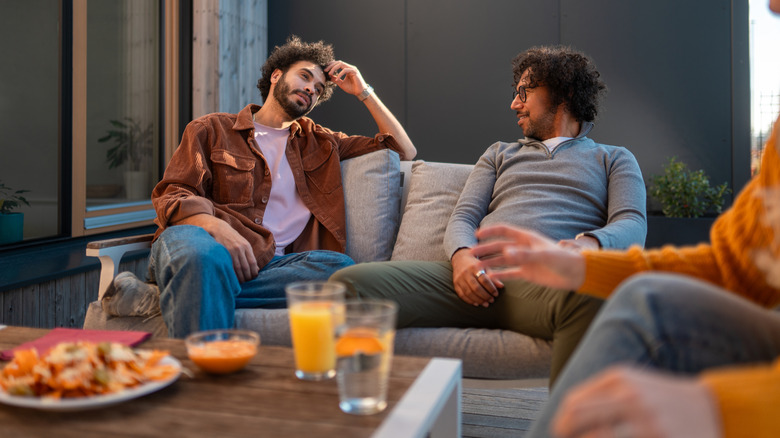 Friends having a conversation while sitting comfortably on an outdoor sofa