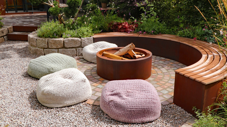 A patio area with a half-moon shaped bench and bean bags centered on a fire pit