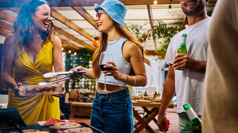 Friends gathered around a grill with a comfortable patio in the background
