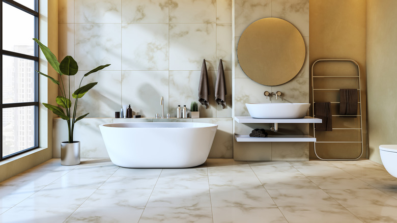 Modern bathroom with white tub and sink and large round vanity mirror