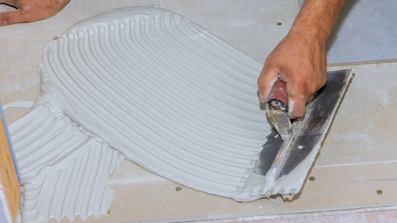 A person preparing a subfloor with adhesive