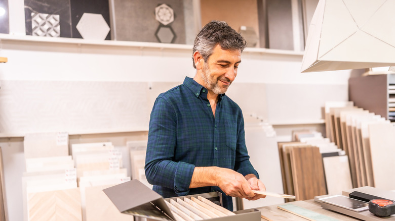 A man in a blue shirt comparing tiling in a flooring showroom