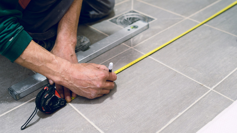 Construction worker measuring a tiled shower floor