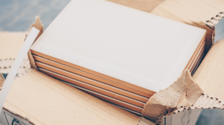 Cream colored ceramic tiles in a open cardboard box