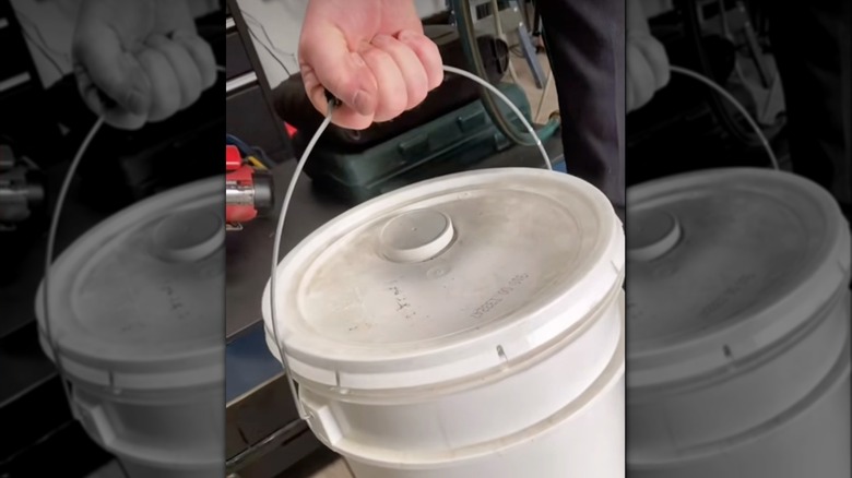 Hand lifting a bucket with rubber handle grip