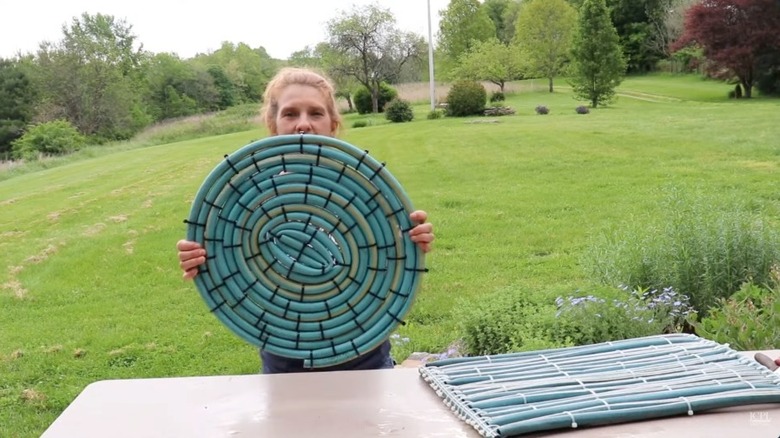 Woman holding up a DIY mat made from a hose