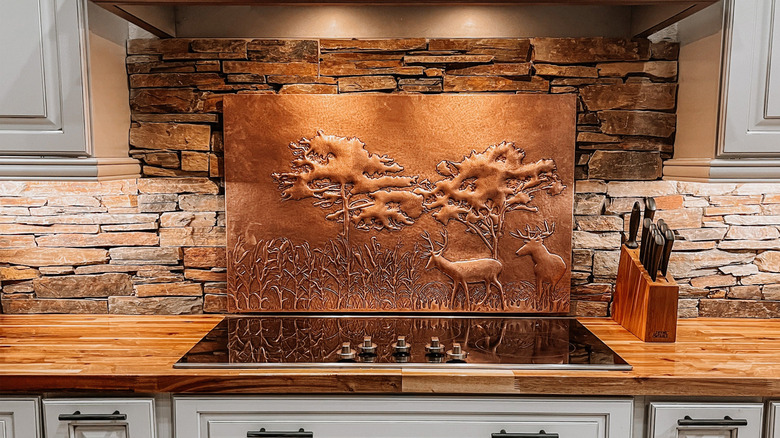 A copper backsplash panel with a woodland deer scene adds warmth to a neutral kitchen design