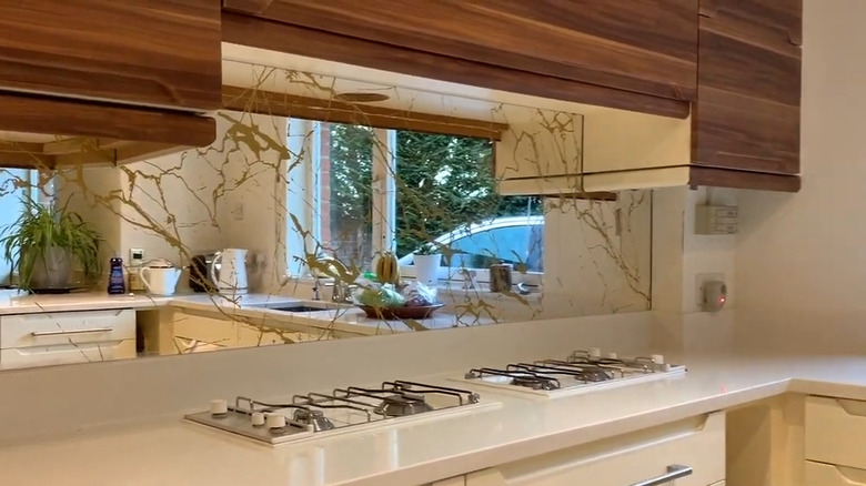 a mirror backsplash above a range reflects like and makes a small kitchen seem larger