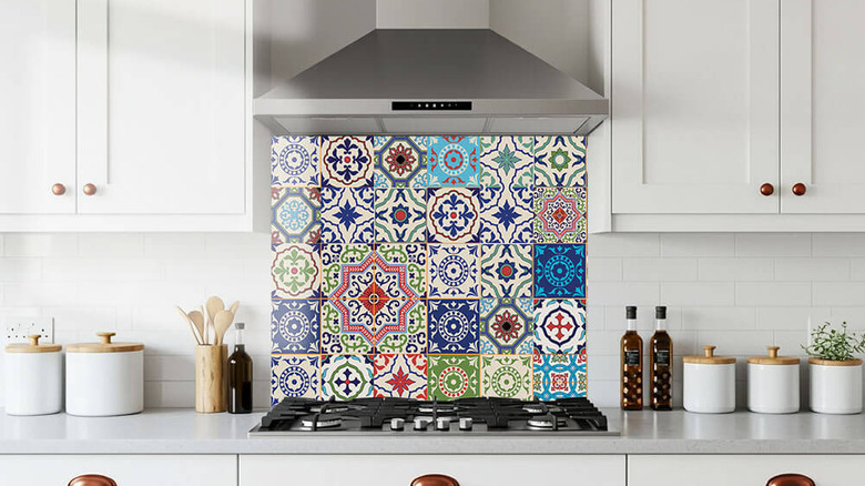 a glass backsplash in a colorful design with white subway tiles