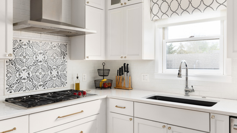 a black and white patterned tile backsplash behind a stove pairs well with the white subway tile in the rest of the kitchen