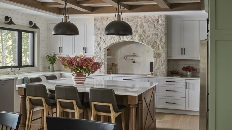 a kitchen with white cabinets and two backsplashes, including marble slab and subway tile backsplash and