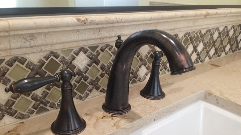 a resin tile with metal and glass inlays provides an elegant mixed material backsplash