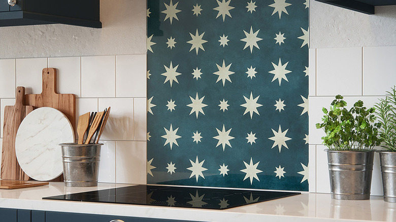 an adhesive backsplash with white multi-pointed stars on a green background with square tiles