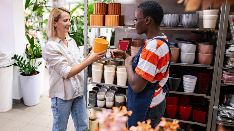 A shop employee helping a customer select a plant pot
