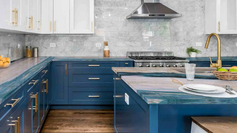 A kitchen with dark blue lower cabinets and a counter and island with blue and gray countertops
