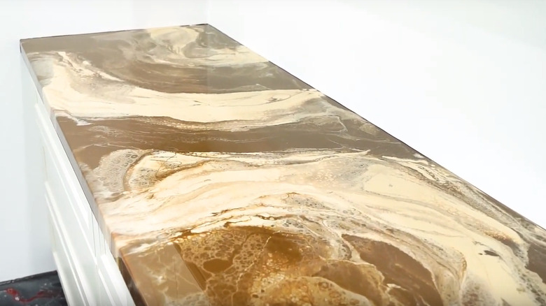 A screenshot from a video showing a counter with a brown and cream marbled epoxy counter