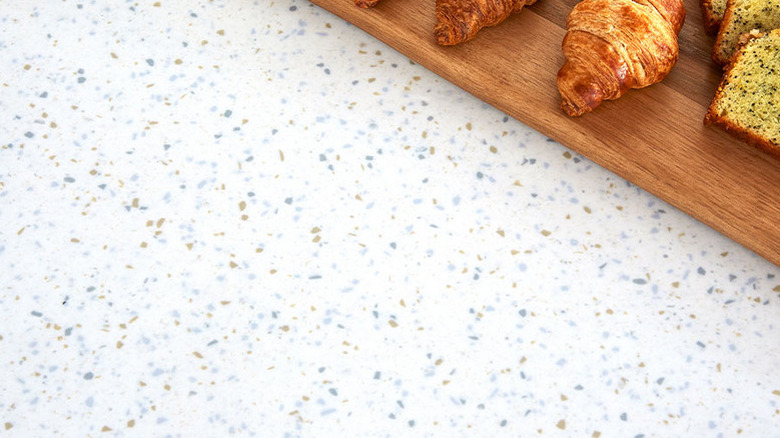 A closeup of a terrazzo counter with small chips and croissants in the corner