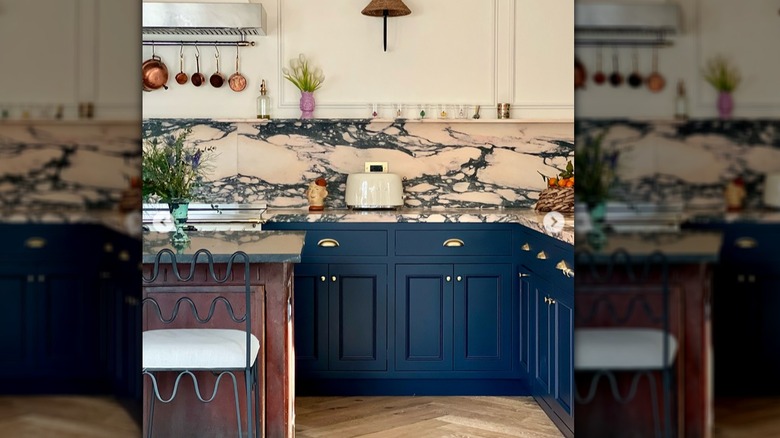 A kitchen with a pinkish and gray countertop and backsplash paired with blue counters